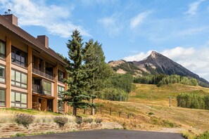 A two-story building with a balcony, a mountain in the background, and a clear sky. - Columbine 2308 (Crested Butte)