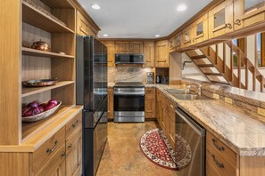 A kitchen with wooden cabinets, stainless steel appliances, a built-in oven, and a granite countertop. - Columbine 2308 (Crested Butte)