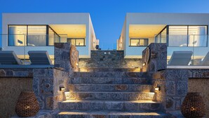 Ein modernes Gebäude mit einer Steintreppe, die zu einem Balkon mit Liegestühlen führt.
