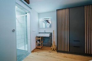 A modern bathroom with a glass shower, a wooden floor, a white sink, and a large mirror. - Nockventure Vacation Home in Gnesau (Gnesau)