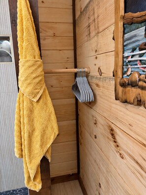 L’intérieur d’un chalet en bois, avec une serviette jaune suspendue à une tringle en bois, un mur en bois avec une fenêtre et une porte en bois.