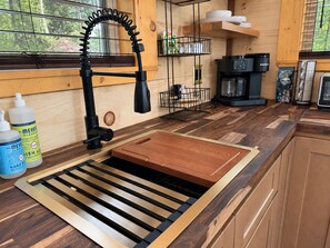 Une cuisine moderne dotée d’un évier encastré, d’une machine à café et d’un plan de travail en bois.