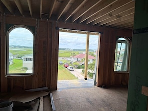 A room with wooden walls and a large open doorway leading to an outdoor area with a view of houses and a road. - Brand New Oceanfront, 10BR, Pool/Spa, & Elevator (Georgetown County)