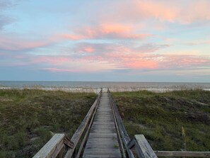 A wooden boardwalk leading to a beach with a view of the ocean and a sunset sky. - Brand New Oceanfront, 10BR, Pool/Spa, & Elevator (Georgetown County)