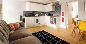 A compact living space with a kitchenette, a sofa, a dining area, and a laundry machine. - Relaxing 3BR | Near Local Stores | Relocation |ST (Oxfordshire)