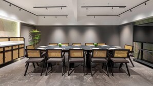 Een moderne vergaderruimte met een lange tafel, stoelen, een televisiescherm en een plant.