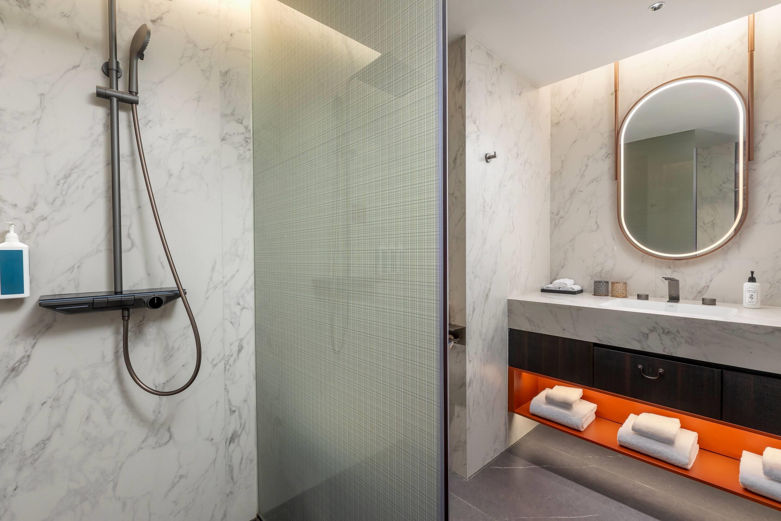 A modern bathroom with a glass-enclosed shower, a vanity with a mirror, and a towel rack.