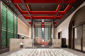 Un vestíbulo amplio con piso estampado, una gran escultura decorativa y un diseño de techo moderno.