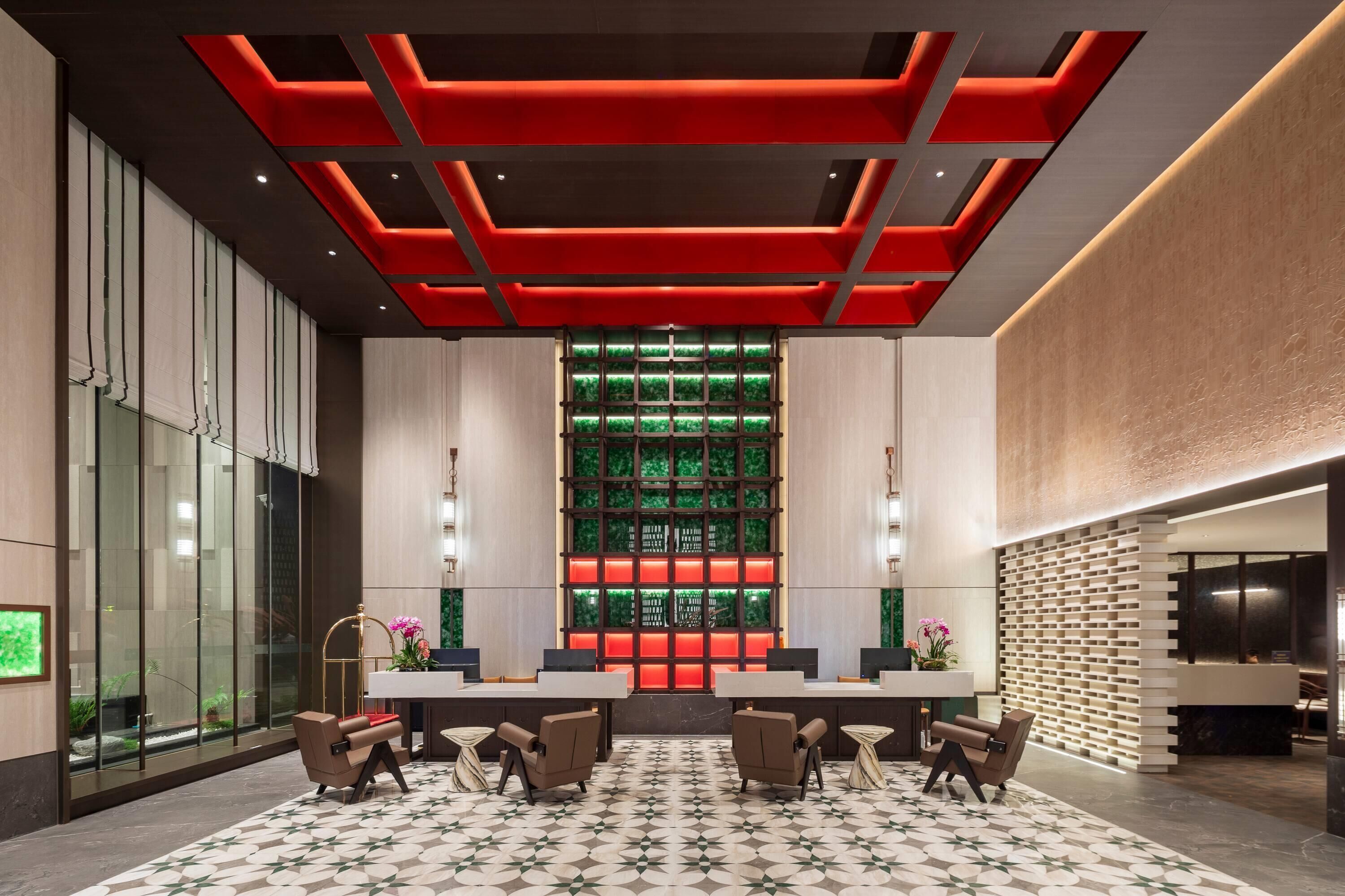 A modern lobby with a reception desk, seating area, and a decorative wall with a green pattern.