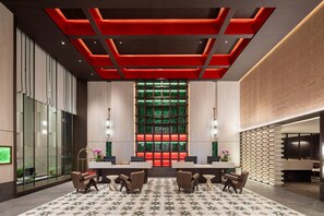 Un vestíbul modern amb taulell de recepció, zona de seients i paret decorativa amb un dibuix verd.