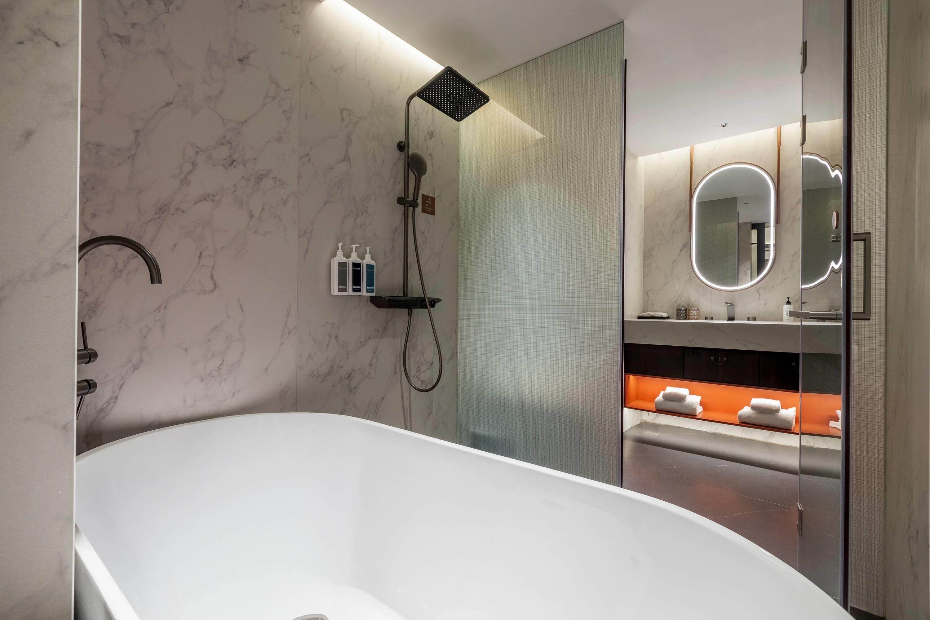 A modern bathroom with a freestanding bathtub, a glass-enclosed shower, and a vanity with a mirror and towel rack.