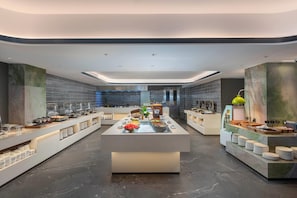 A modern breakfast buffet with a central serving area, multiple food stations, and a clean, contemporary design.