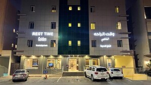 A multi-story hotel with 'REST TIME Golden' and 'قوة الراحة' signage, a parking area with cars, and a well-lit entrance. - Rest Time Golden Hotel (Riyadh)