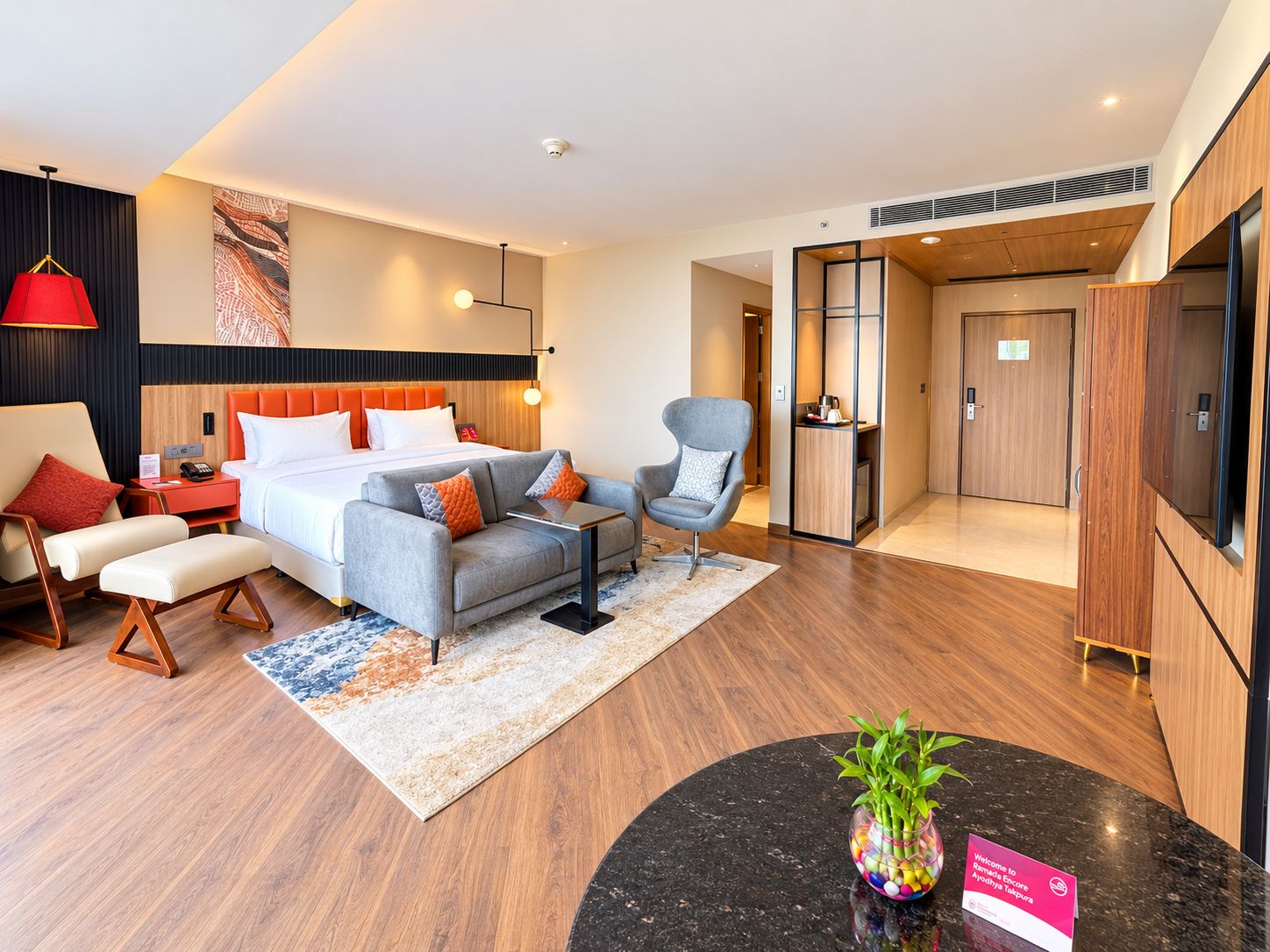 Une chambre d’hôtel moderne équipée d’un lit, d’un coin salon et d’une petite table agrémentée d’une plante.