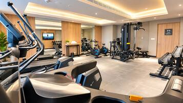 A modern gym with various exercise equipment, a television, and a sign indicating it's open 24/7.