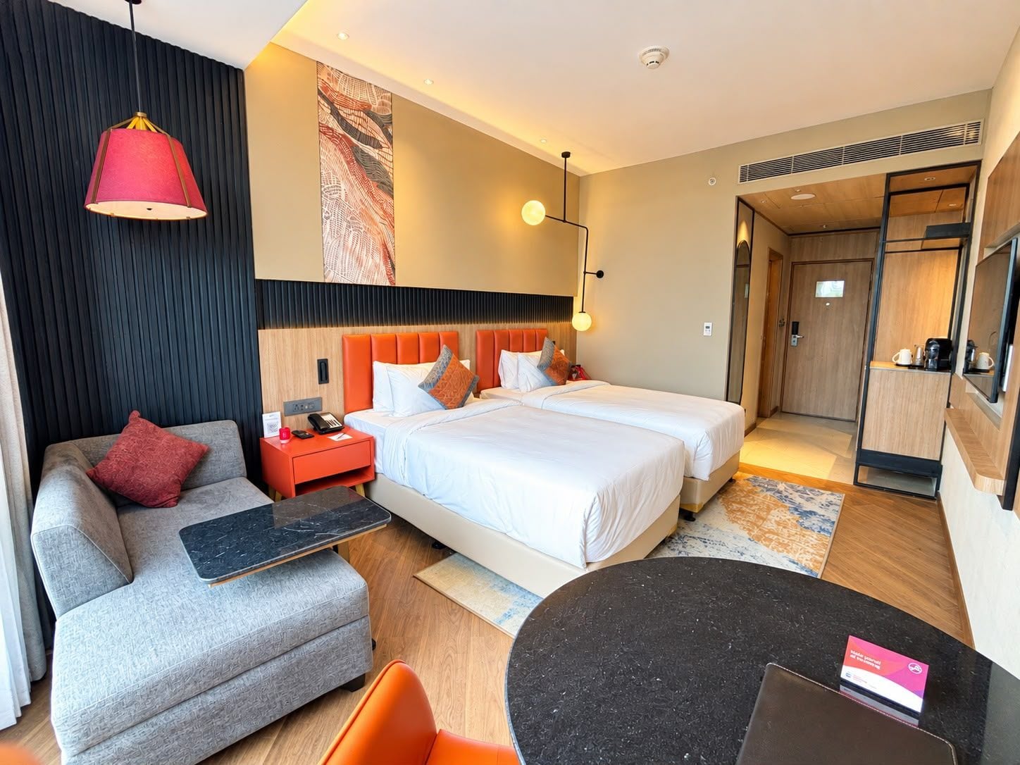 A hotel room with a bed, a sofa, a desk, and a dining table.