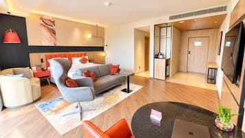 Une chambre d’hôtel moderne avec un canapé, un fauteuil et un coin repas équipé d’un ordinateur portable et d’un vase.