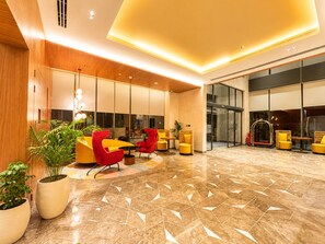 A modern lobby with a central seating area, large windows, and a polished floor. - Ramada Encore By Wyndham Ayodhya Takpura (Faizabad)
