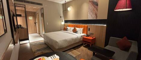 Habitación de hotel con cama, escritorio, silla, mesa de comedor con fruta y sofá.