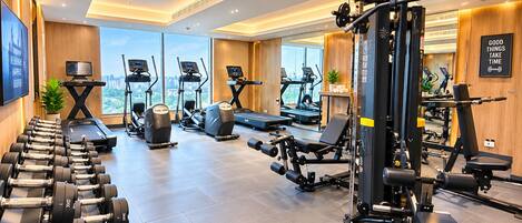 Un gimnasio moderno con máquinas de cardio, pesas libres y banco para ejercicios de fuerza.