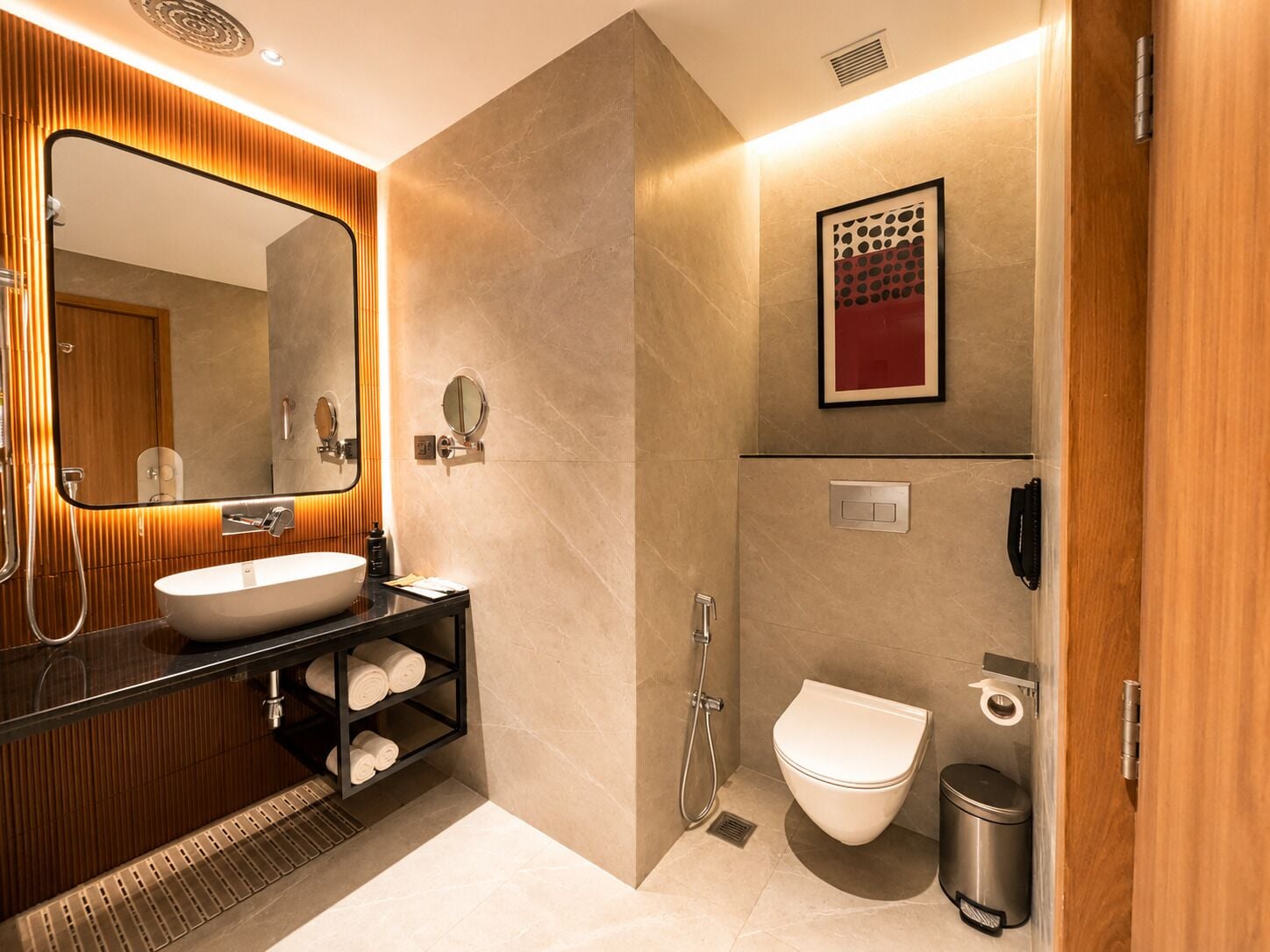 A modern bathroom with a large mirror, a sink, a toilet, and a shower.