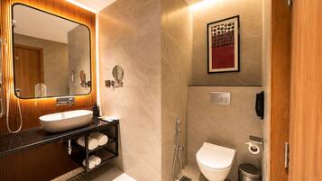 A modern bathroom with a large mirror, a sink, a toilet, and a shower.