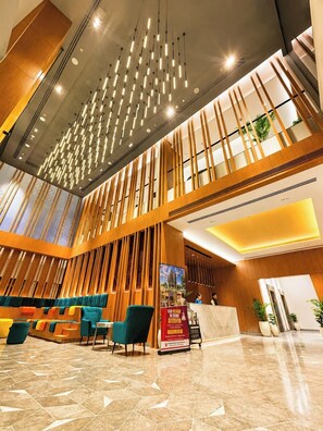 A hotel lobby with a reception desk, seating area, and a modern ceiling design. - Ramada Encore By Wyndham Ayodhya Takpura (Faizabad)