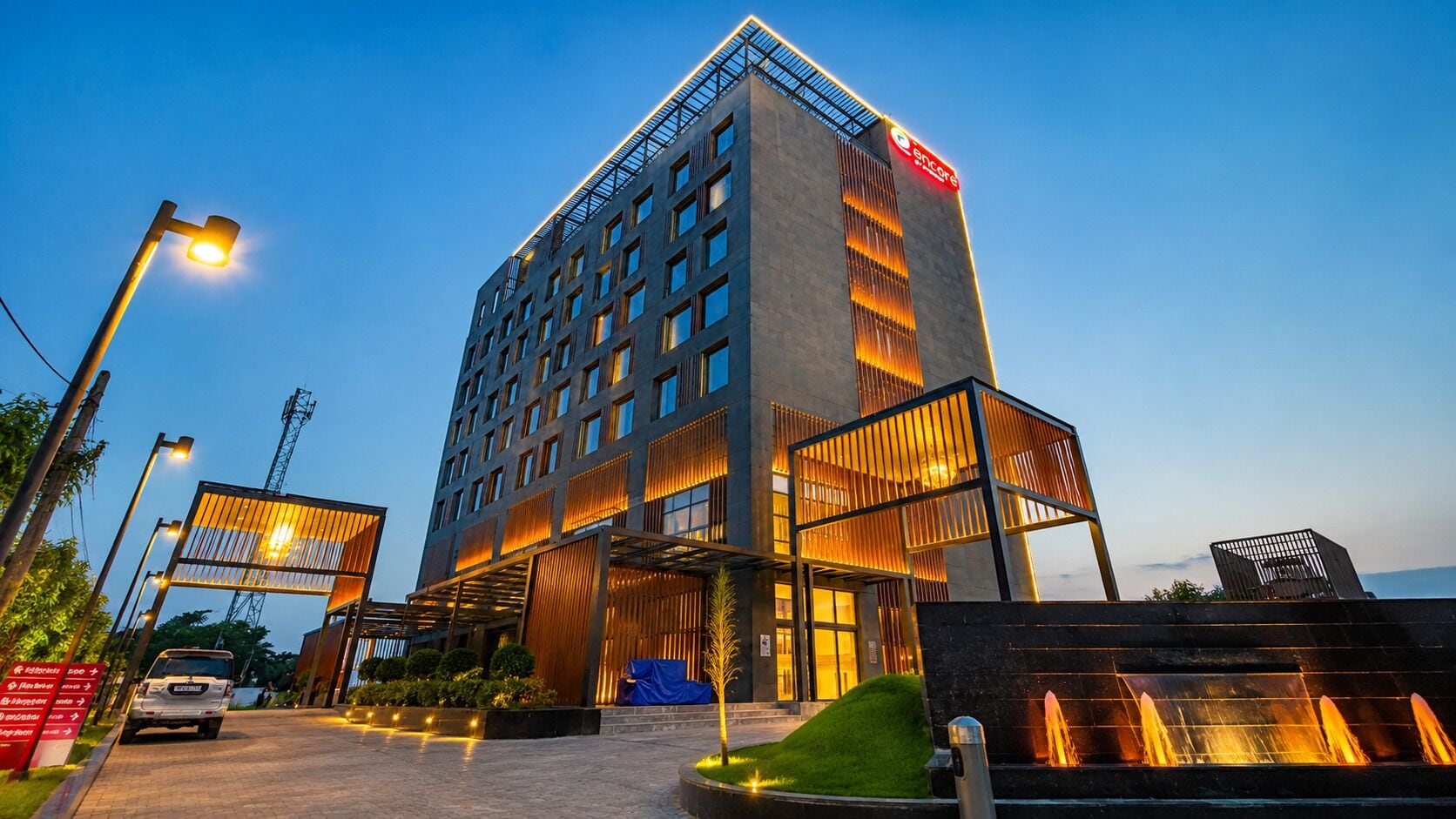 Un hotel moderno con una entrada destacada, varios pisos y una fachada bien iluminada.