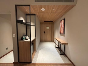 A hallway with a wooden bench, a door at the end, and a wall-mounted picture. - Ramada Encore By Wyndham Ayodhya Takpura (Faizabad)