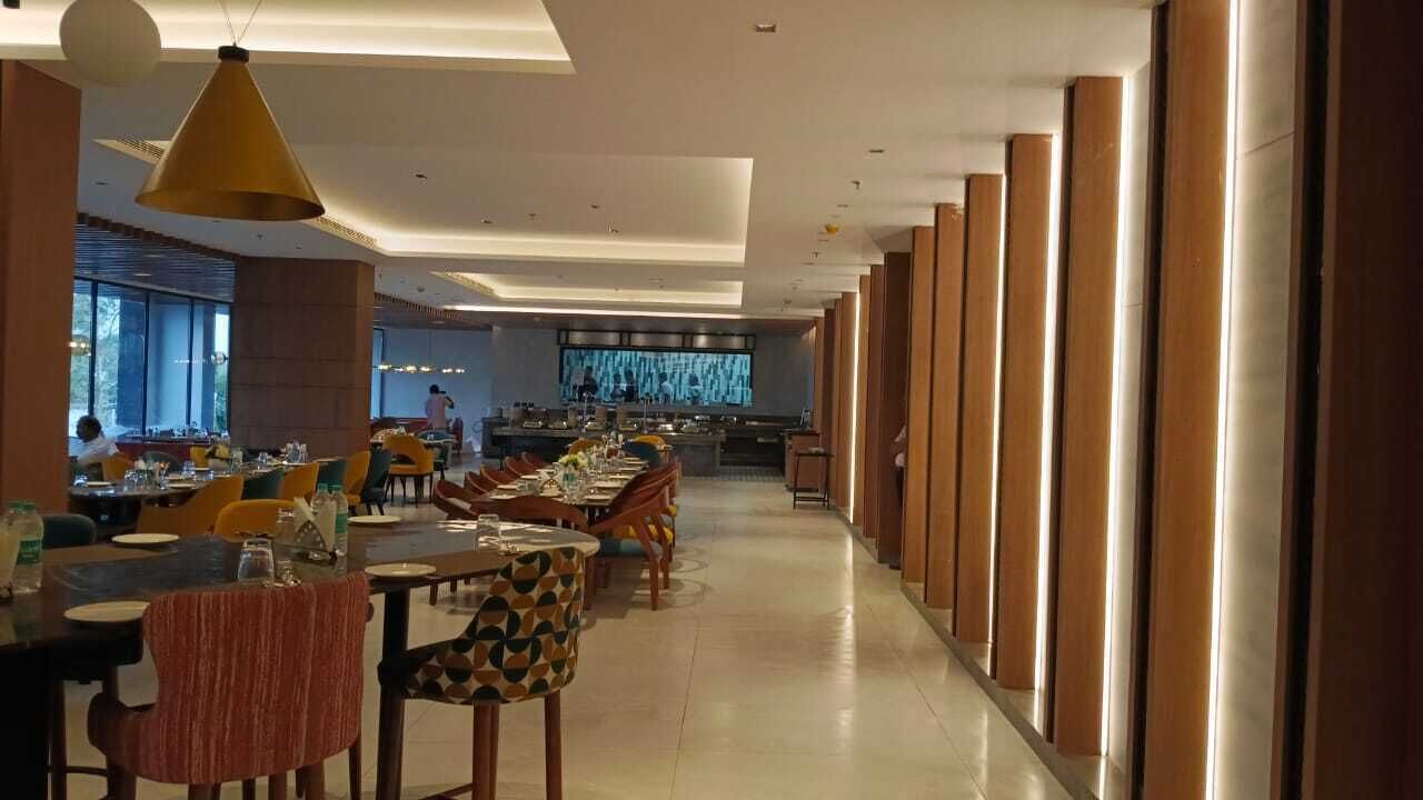 Un área de comedor moderna con mesas largas, sillas y una cocina central.