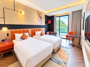 Habitación de hotel con dos camas, un sofá, una mesa de comedor y un televisor.