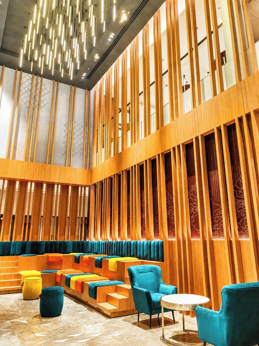 A modern interior with a seating area featuring colorful cushions and a high ceiling with a unique light fixture.