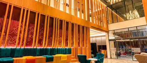Um lobby moderno com área de estar, escada e ampla entrada de vidro.