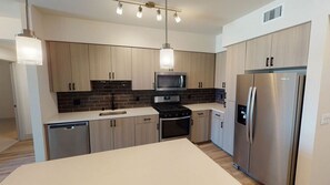 A modern kitchen with stainless steel appliances, wooden cabinets, and pendant lighting. - Spacious 2BR Stay w Pool at Embark Apartments (Fremont)