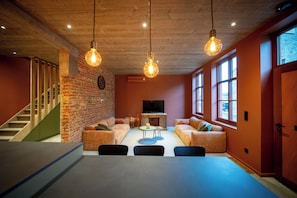 A modern living room with a brick wall, wooden ceiling, and large windows. - A warm, cozy vacation home where you always feel right at home (Poperinge)