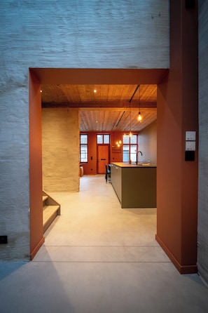 A modern interior with a kitchen area, wooden ceiling, and a view through a doorway. - A warm, cozy vacation home where you always feel right at home (Poperinge)