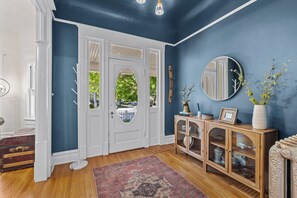 A hallway with a blue wall, a white door, a wooden cabinet, and a patterned rug. - North End Retreat Near Hyde Park (Boise)