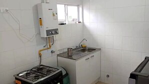 A compact kitchen with a gas stove, a built-in oven, a sink, and a window above the sink. - Cabin in Coyhaique: Explore the Carretera Austral (Coyhaique)