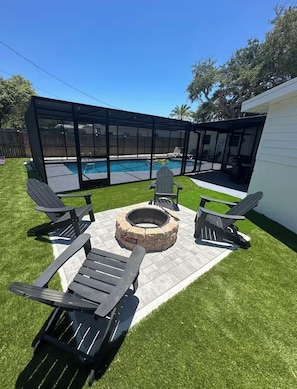 A backyard with a swimming pool, a fire pit, and outdoor seating.