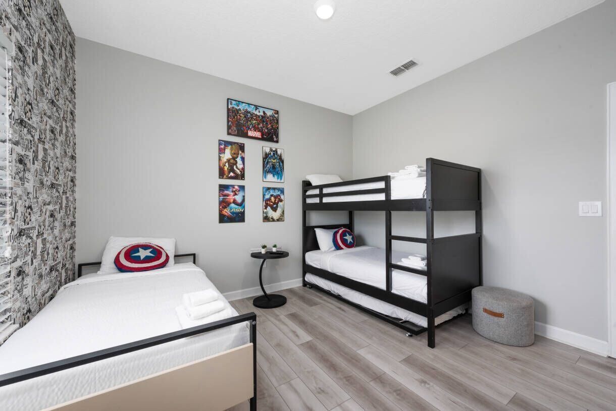 Um quarto com uma cama de solteiro, uma cama individual, uma mesa pequena e cartazes nas paredes.
