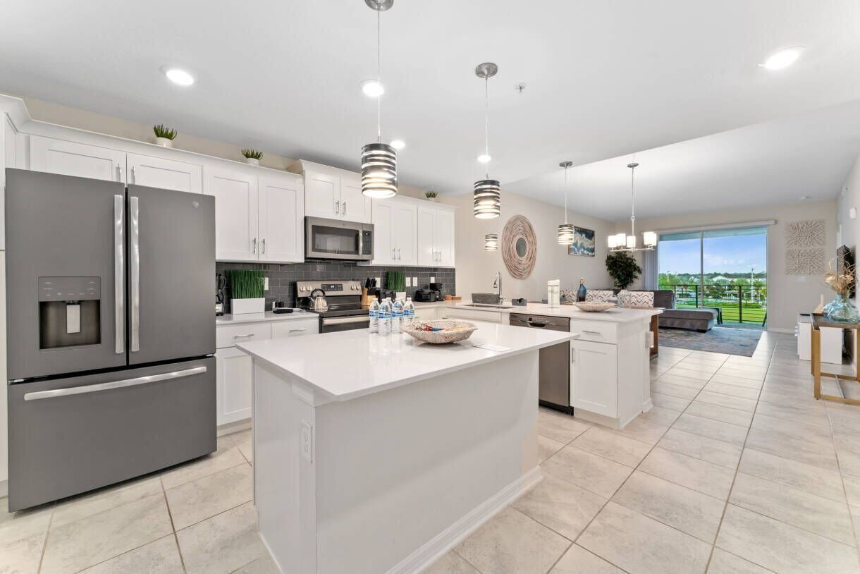 A modern kitchen with a central island, stainless steel appliances, and pendant lighting.