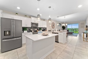A modern kitchen with a central island, stainless steel appliances, and pendant lighting. - 5BR Storey Lake Home Near Disney With Pool (Kissimmee)