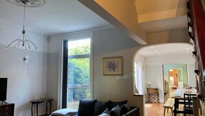 Un salon avec un canapé, un téléviseur, une table et une grande fenêtre.