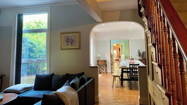 Un vaste espace de vie comprenant un canapé, une table à manger dressée pour un repas et un escalier menant à l’étage supérieur.