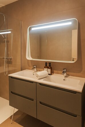 Een badkamer met een dubbele wastafel, een grote spiegel en een douche.