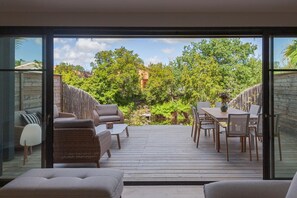Eine Terrasse mit Gartenmöbeln, einem Esstisch und Stühlen.