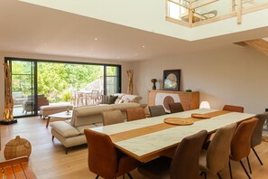 Een ruime woonkamer met een eettafel, banken en uitzicht op de omgeving.