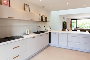 Een moderne keuken met witte kasten, een zwart aanrecht en een raam dat natuurlijk licht binnenlaat.