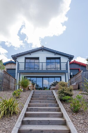 Een huis met twee verdiepingen, een balkon, een trap en een houten omheining.
