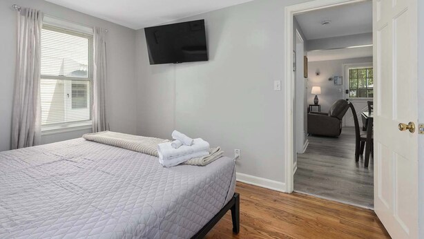 Een slaapkamer met een bed, een flatscreen televisie en uitzicht op een eetruimte.